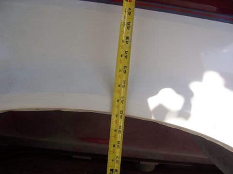 1991 Ford Bronco - A measuring tape is placed against the side of a white vehicle's fender to document lift kit measurements.