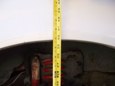 1991 Ford Bronco - A tape measure is used to record suspension height, showing a red coil spring and shock absorber.