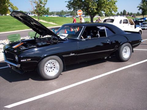 1972 Ford Ranchero - A black 1969 Chevrolet Camaro is parked with its hood up, revealing the engine and a 350 badge.