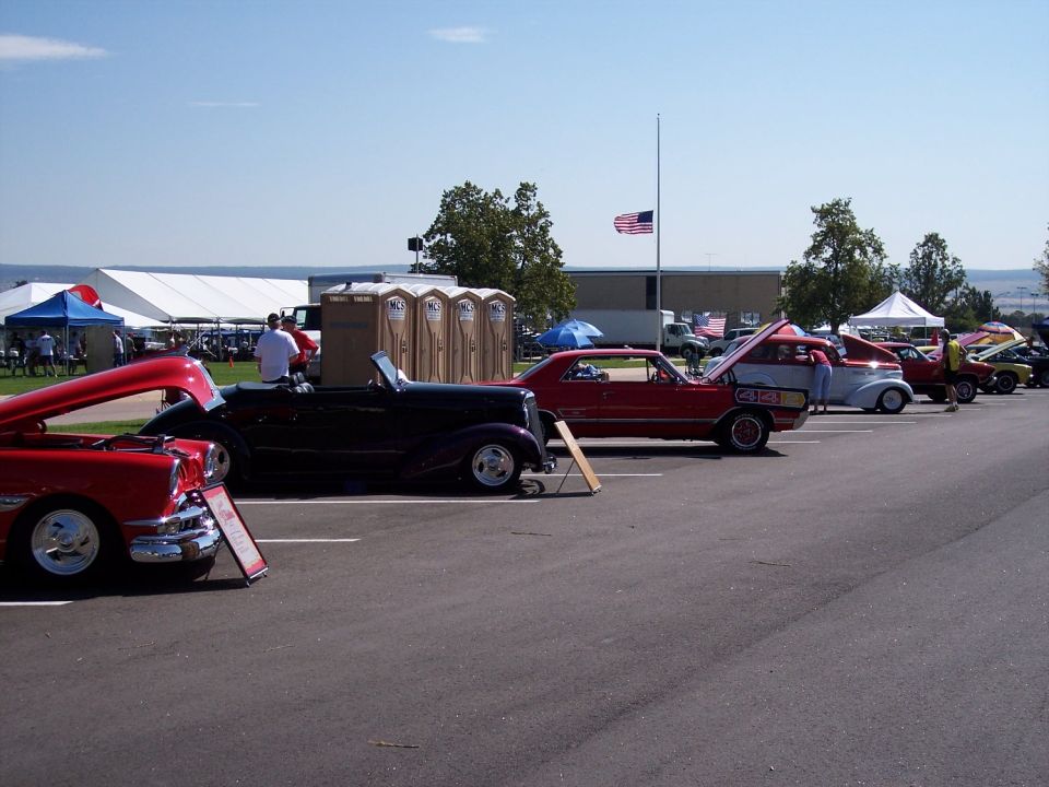 Red car with hood open at car show
