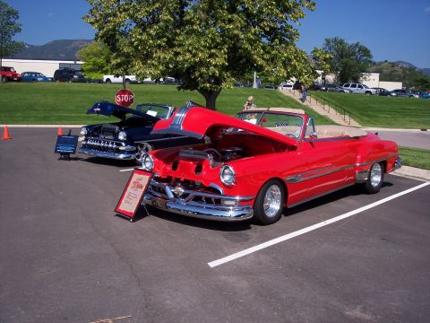 1972 Ford Ranchero - A red convertible and a dark blue convertible are parked side-by-side at an outdoor event.