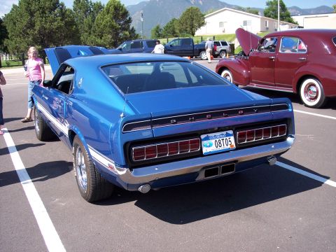 1972 Ford Ranchero - A blue muscle car with racing stripes and Shelby badging is parked in a lot with other vehicles.