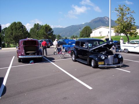 1972 Ford Ranchero - Two classic cars are parked in a lot with their hoods or trunks open, with mountains visible in the distance.