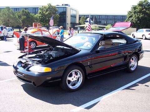 1972 Ford Ranchero - A black convertible sports car is displayed with its hood open, parked outdoors with other vehicles present.