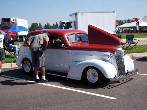 1972 Ford Ranchero - A person examines a vintage two-tone red and white automobile at an outdoor event.