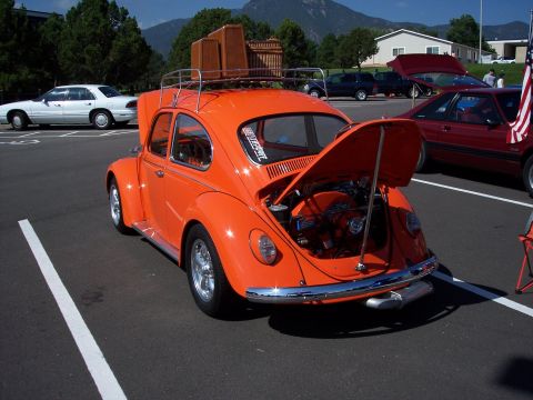1972 Ford Ranchero - Orange Volkswagen Beetle with luggage rack and open engine compartment, parked at an outdoor event.