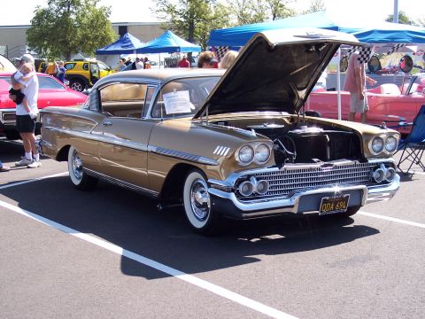1972 Ford Ranchero - A gold 1958 Chevrolet Apache pickup truck is displayed with its hood open at an outdoor event. The license plate reads QDA 694.