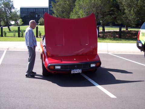 1972 Ford Ranchero - An older man stands next to a red Ferrari with its hood open in a parking lot.