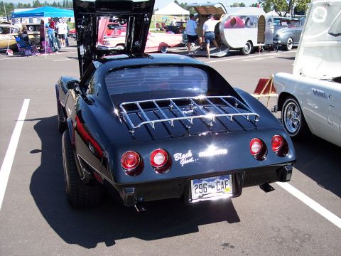1972 Ford Ranchero - Rear view of a black sports car with its hood and trunk open, parked at an outdoor event.