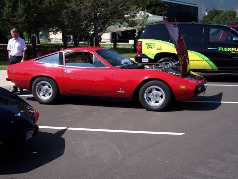 1972 Ford Ranchero - A red sports car is parked in a lot with its hood open, revealing the engine bay.