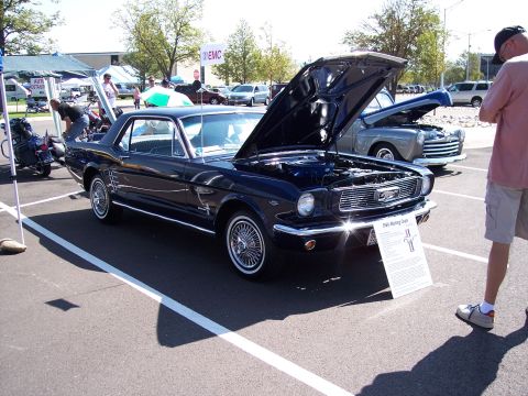 1972 Ford Ranchero - A dark blue 1965 Ford Mustang coupe is displayed with its hood open, alongside other vehicles and tents.