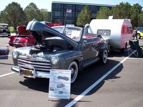 1972 Ford Ranchero - A classic convertible is displayed with its hood open, parked next to a vintage trailer.