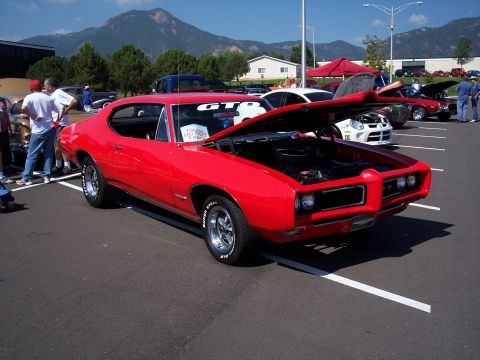1972 Ford Ranchero - A red 1969 Pontiac GTO is displayed with its hood open at an outdoor car show.