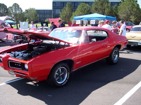 1972 Ford Ranchero - A red Pontiac GTO is displayed with its hood up at an outdoor event.