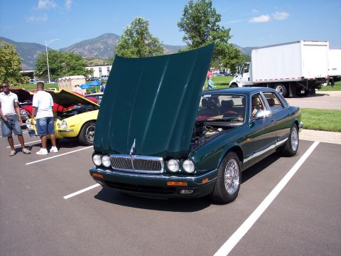 1972 Ford Ranchero - A green Jaguar XJ sedan is displayed with its hood open at an outdoor car show.
