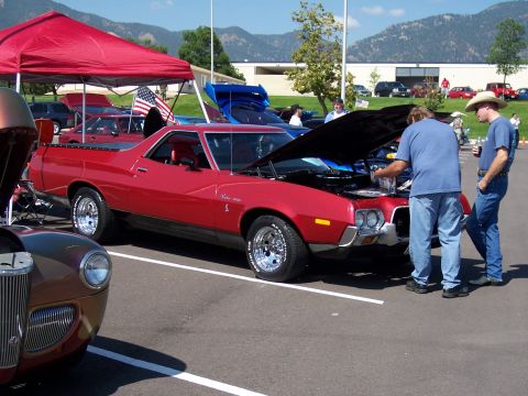 1972 Ford Ranchero - Red 1972 Ford Ranchero pickup truck at a car show with its hood open, attended by two men.