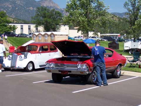1972 Ford Ranchero - A red muscle car, possibly a 1969 Chevrolet Chevelle SS, is displayed with its hood open at an outdoor event.