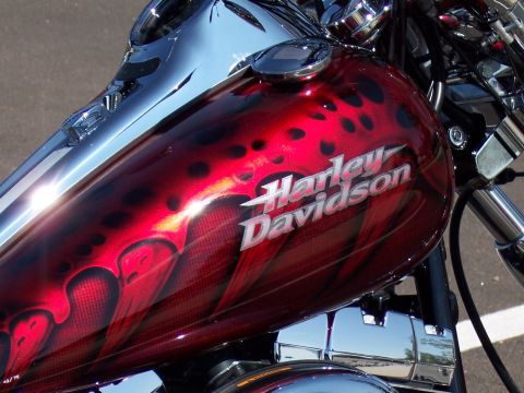 1972 Ford Ranchero - The gas tank of a Harley-Davidson motorcycle features a custom red paint job with black spots and flame accents.