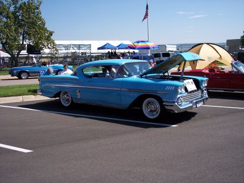 1972 Ford Ranchero - A blue 1958 Chevrolet Bel Air coupe is displayed with its hood open at an outdoor event.