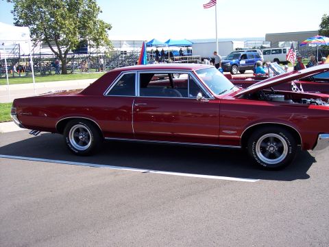 1972 Ford Ranchero - A maroon coupe with its hood open sits on asphalt, with other vehicles and tents in the background.