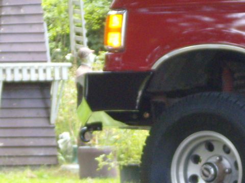 1989 Ford Bronco - Close-up of the rear section of a red SUV, focusing on the bumper and wheel.