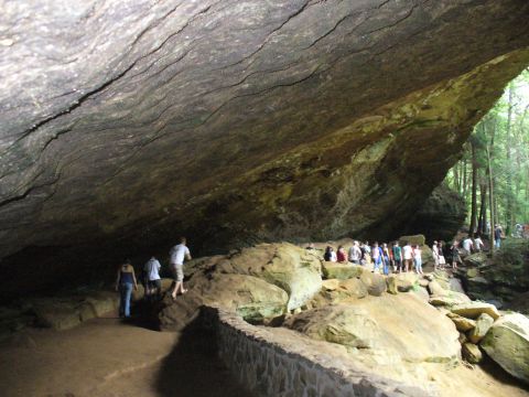 1991 Ford Probe - A group of people explore a natural rock formation with a stone wall bordering the path.