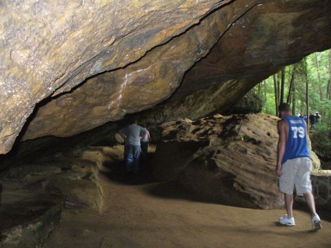 1991 Ford Probe - People explore a large cave with natural rock formations and trees visible in the background.