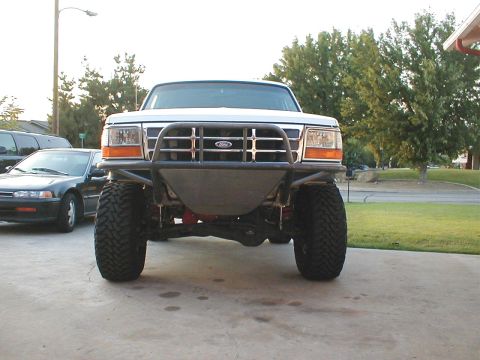 1996 Ford Bronco - A white Ford Bronco with a custom bumper and large tires is parked in a driveway.