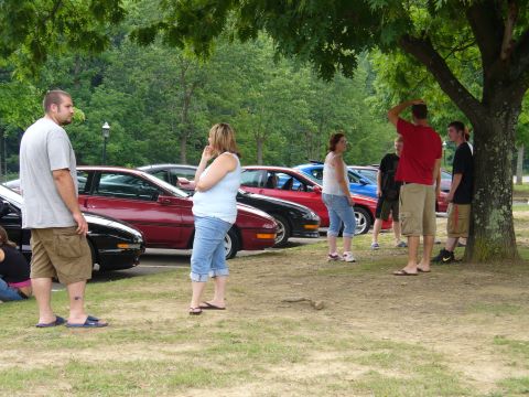 1991 Ford Probe - A group of people stand near several cars, including a red 1991 Ford Probe.