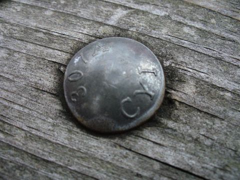1991 Ford Probe - A metal cap with stamped markings sits on a wooden surface.