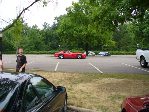 1991 Ford Probe - A red convertible sports car is parked in a lot, with other vehicles and trees in the background.