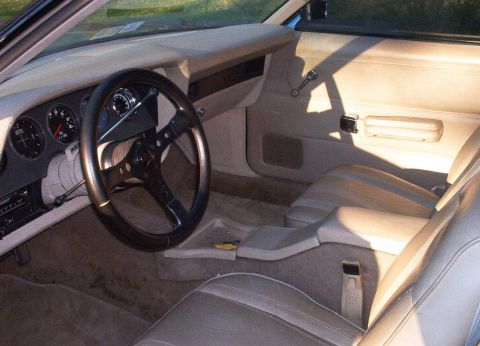 1990 Ford F-250 - The interior of a car shows beige upholstery, a custom steering wheel, and the dashboard with gauges.