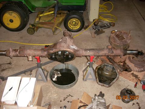 2000 Chevrolet Tahoe - A disassembled differential axle assembly sits on jack stands in a garage setting.