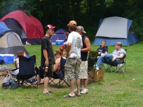 1991 Ford Probe - A group of people are seen relaxing at a campsite with several tents set up in the background.