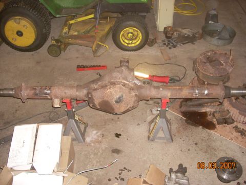 2000 Chevrolet Tahoe - Rear axle assembly on jack stands, with a lawn tractor visible in the background.