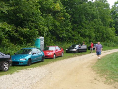 1991 Ford Probe - A group of Honda Civics are parked on the side of a dirt road, with people standing around them.