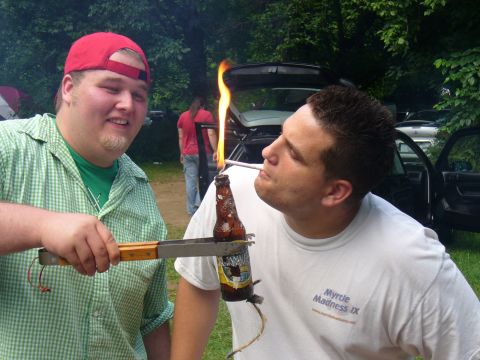 1991 Ford Probe - Two men are at a picnic, one is holding a flaming beer bottle with tongs while the other lights it.