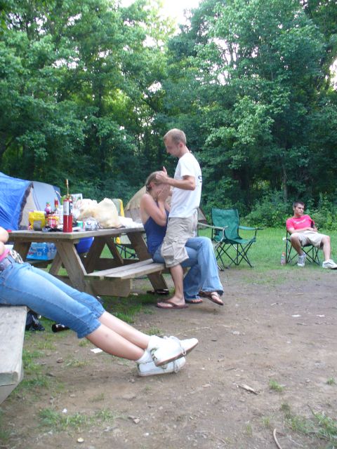 1991 Ford Probe - A group of people are gathered at a campsite, with some sitting at a picnic table and others relaxing nearby.