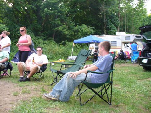 1991 Ford Probe - A group of people relax at a campsite with an RV and a black car visible.