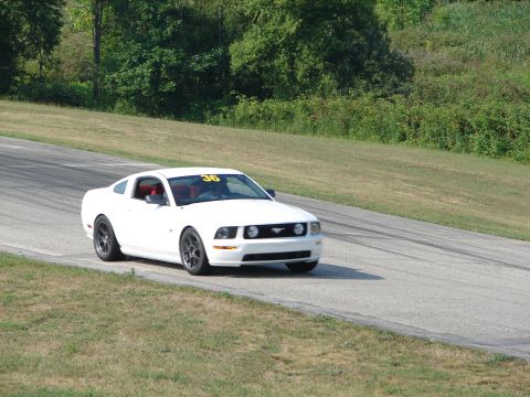1993 Ford Taurus - A white Ford Mustang with racing number 36 on the windshield navigates a turn on a road course.