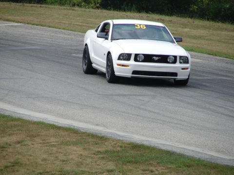 1993 Ford Taurus - A white Ford Mustang is captured on a race track, displaying the number 36 on its windshield.