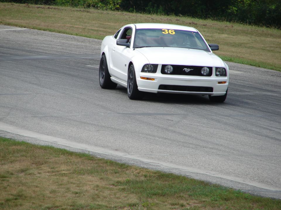 White Ford Mustang with number 36 on windshield driving on a race track