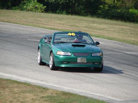 1993 Ford Taurus - A green convertible sports car with a racing number on the windshield navigates a road course.