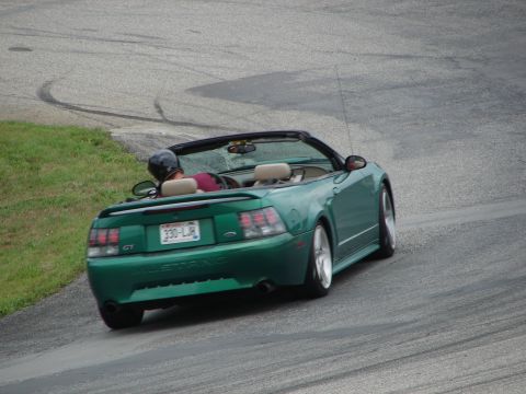 1993 Ford Taurus - Green convertible Mustang GT on a race track with tire marks visible.