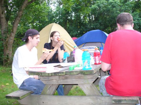 1991 Ford Probe - Friends enjoy a meal outdoors at a campsite, with tents providing shelter in the background.