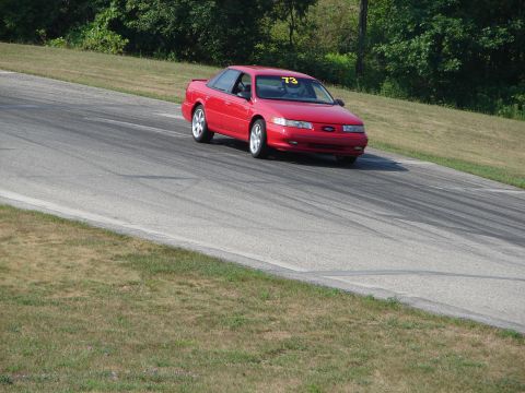 1993 Ford Taurus - Red 1993 Ford Taurus driving on a road course with number 73 visible on the windshield.