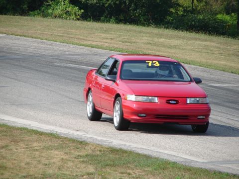 1993 Ford Taurus - A red 1993 Ford Taurus is seen on a race track with the number 73 displayed on its windshield.