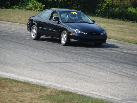 1993 Ford Taurus - A black sedan with racing number 75 is seen on a race track.