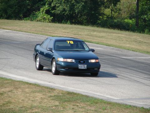 1993 Ford Taurus - A 1993 Ford Taurus with racing number 78 navigates a turn on a paved road course.