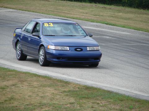 1993 Ford Taurus - A blue 1993 Ford Taurus competes on a road course, displaying the number 83 on its windshield.